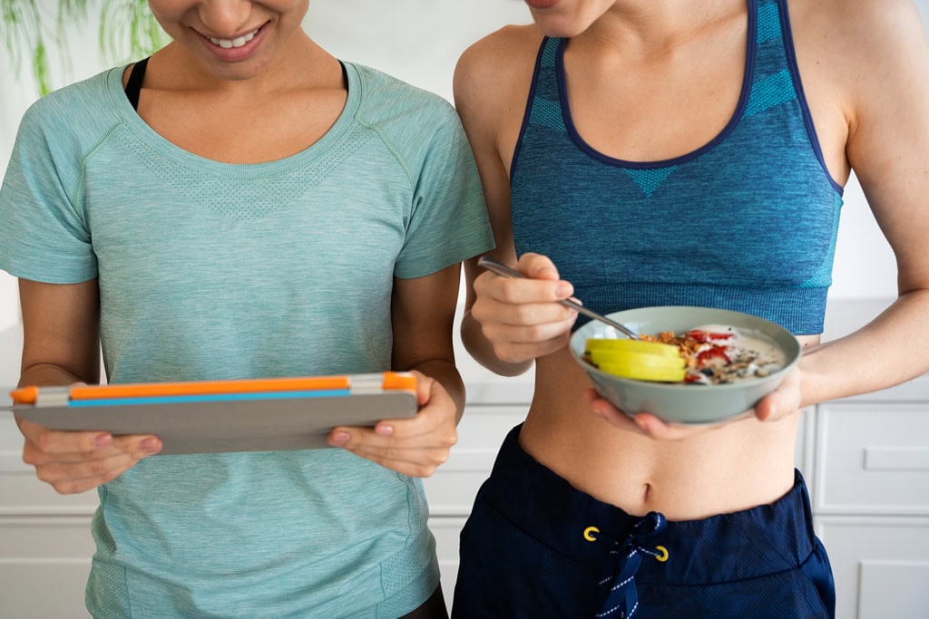 Two woman doing meal plan while eating healthy food
